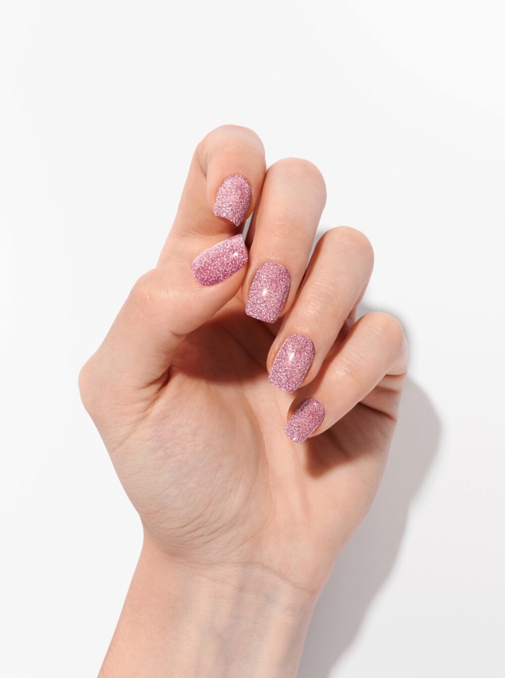 Getragene Nagelfolien mit rosafarbenem Glitzer als Alternative zu Gel für künstliche Nägel